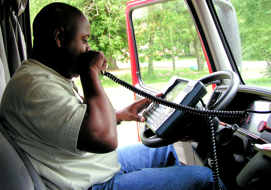 African American Truck Driver Using A Onboard Computer And CB Ra