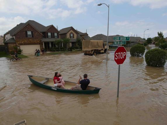 A woman holds a baby in a canoe as Texas Guardsmen arrive to assist after flooding in Brookshire, Texas, U.S. April 20, 2016.   U.S. Army National Guard/1st Lt. Zachary West/Handout via REUTERS