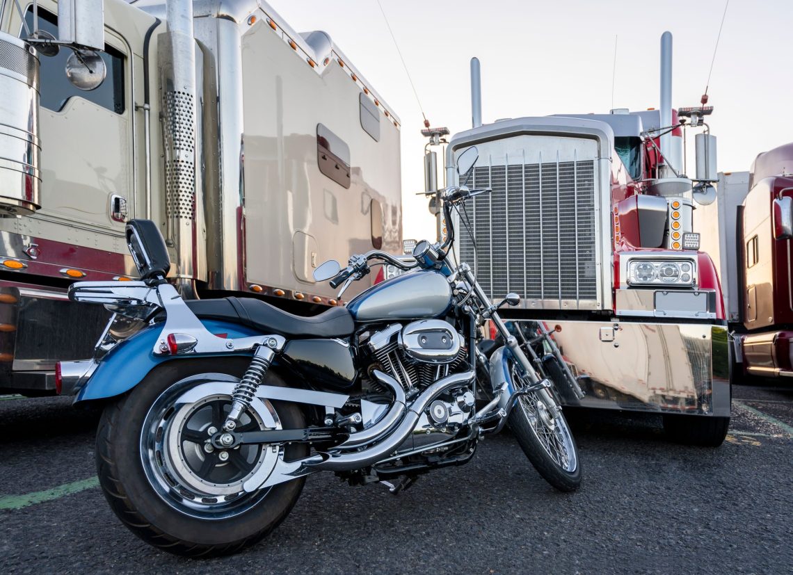 A motorcycle parked in front of two 18-wheeler trucks.