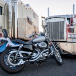 A motorcycle parked in front of two 18-wheeler trucks.