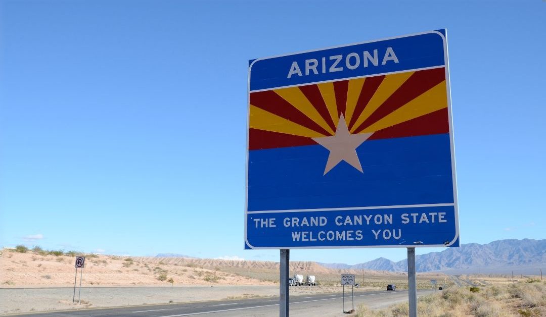 A blue Arizona highway sign standing tall against a clear blue sky