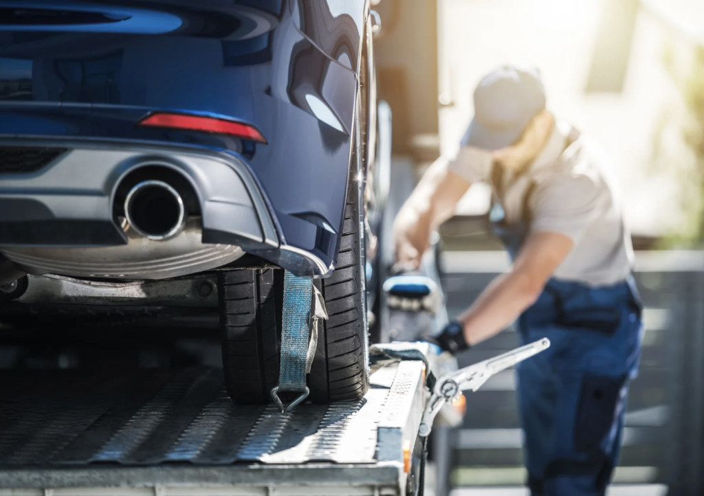 Preparations for car shipping with a man putting car on truck.