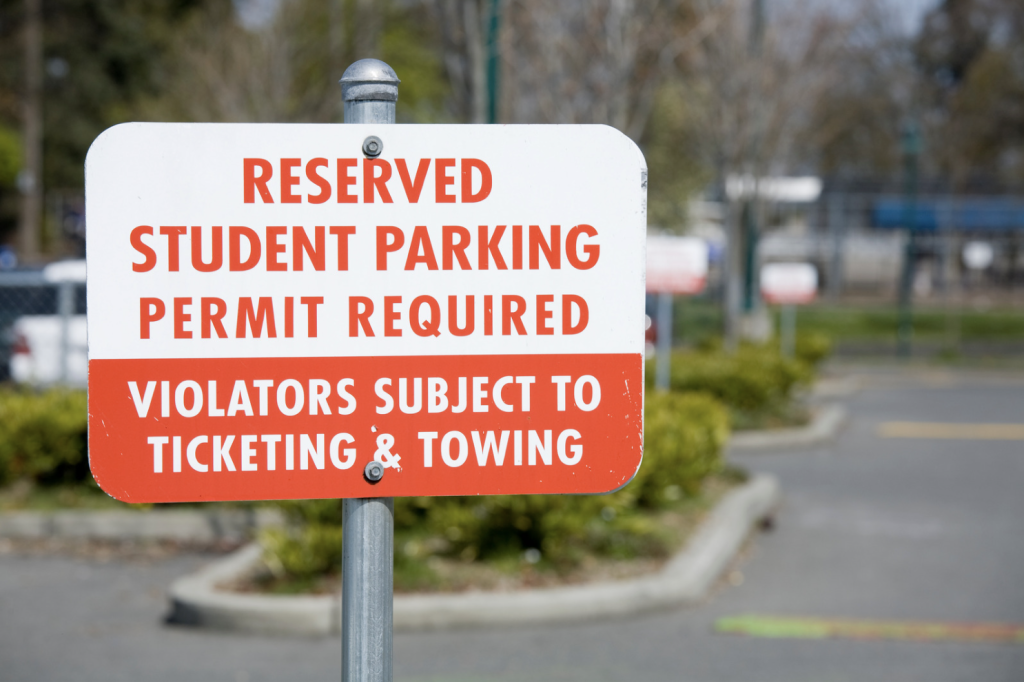 Student parking at college campus with sign for parking permit.