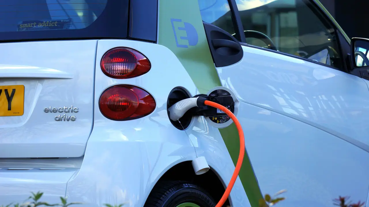 White and green electric car charging at charging station prepare for car shipping.